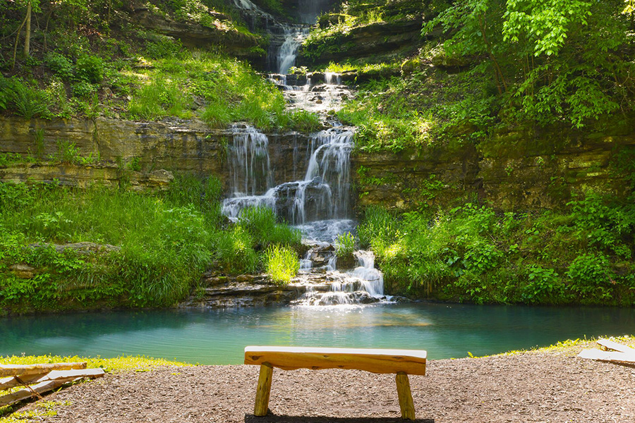 A tiered waterfall spilling into a turquoise stream at Dogwood Canyon Nature Park.