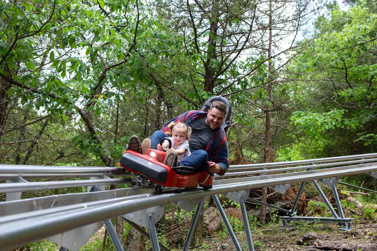 A parent and child riding the Copperhead Mountain Coaster at Shepherd of the Hills.